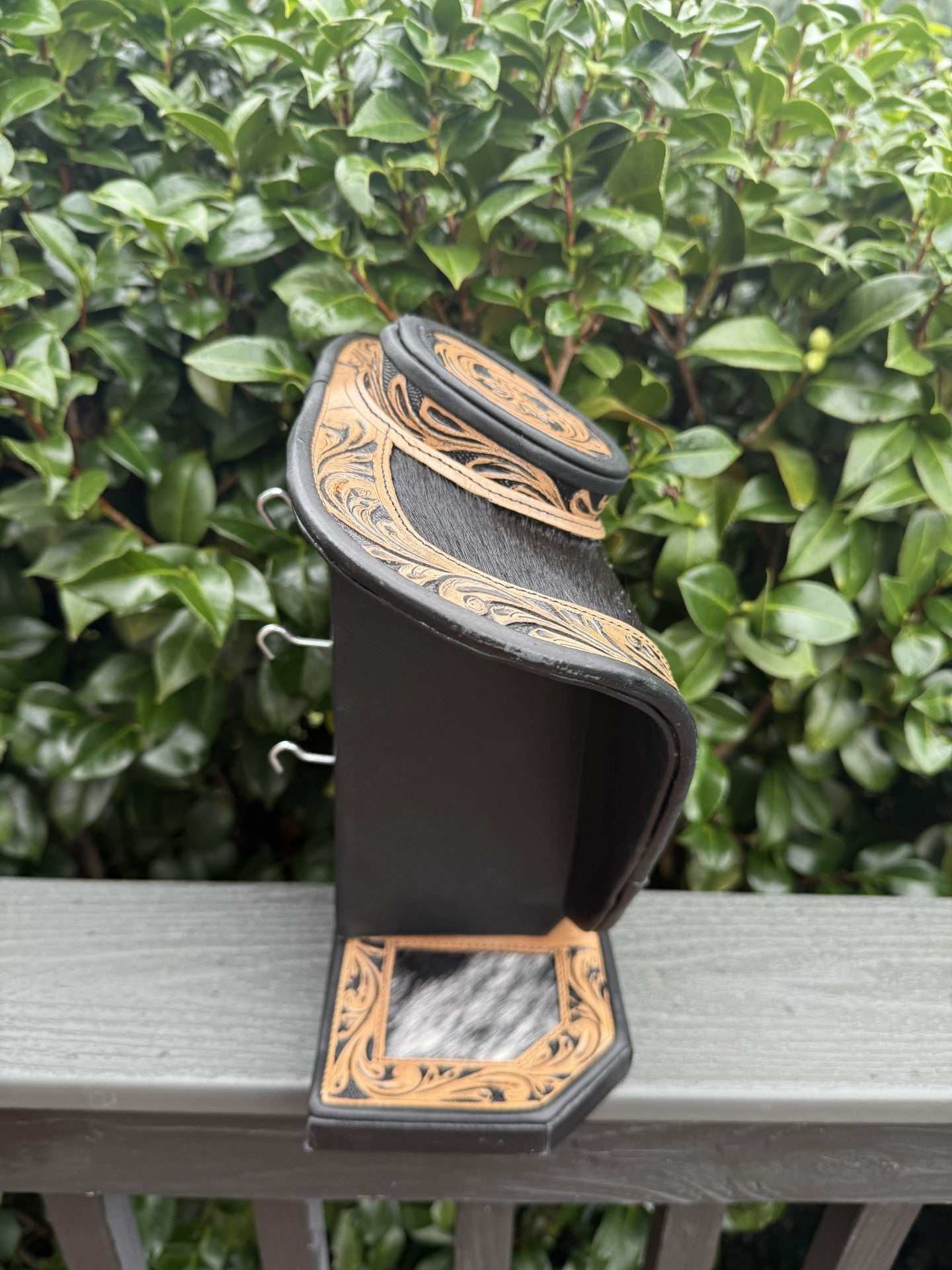 Black and brown tooled leather and cowhide necklace display stand with intricate design
