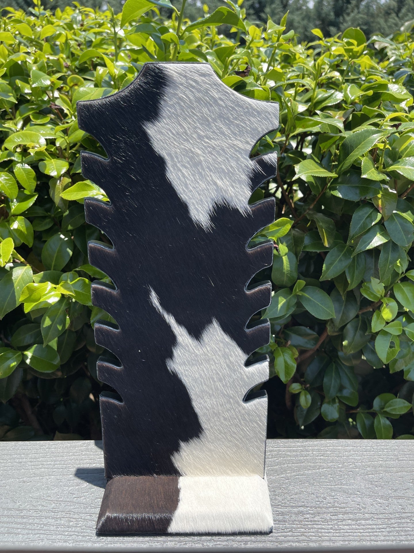 Black and white cowhide necklace display with rustic design for jewelry organization