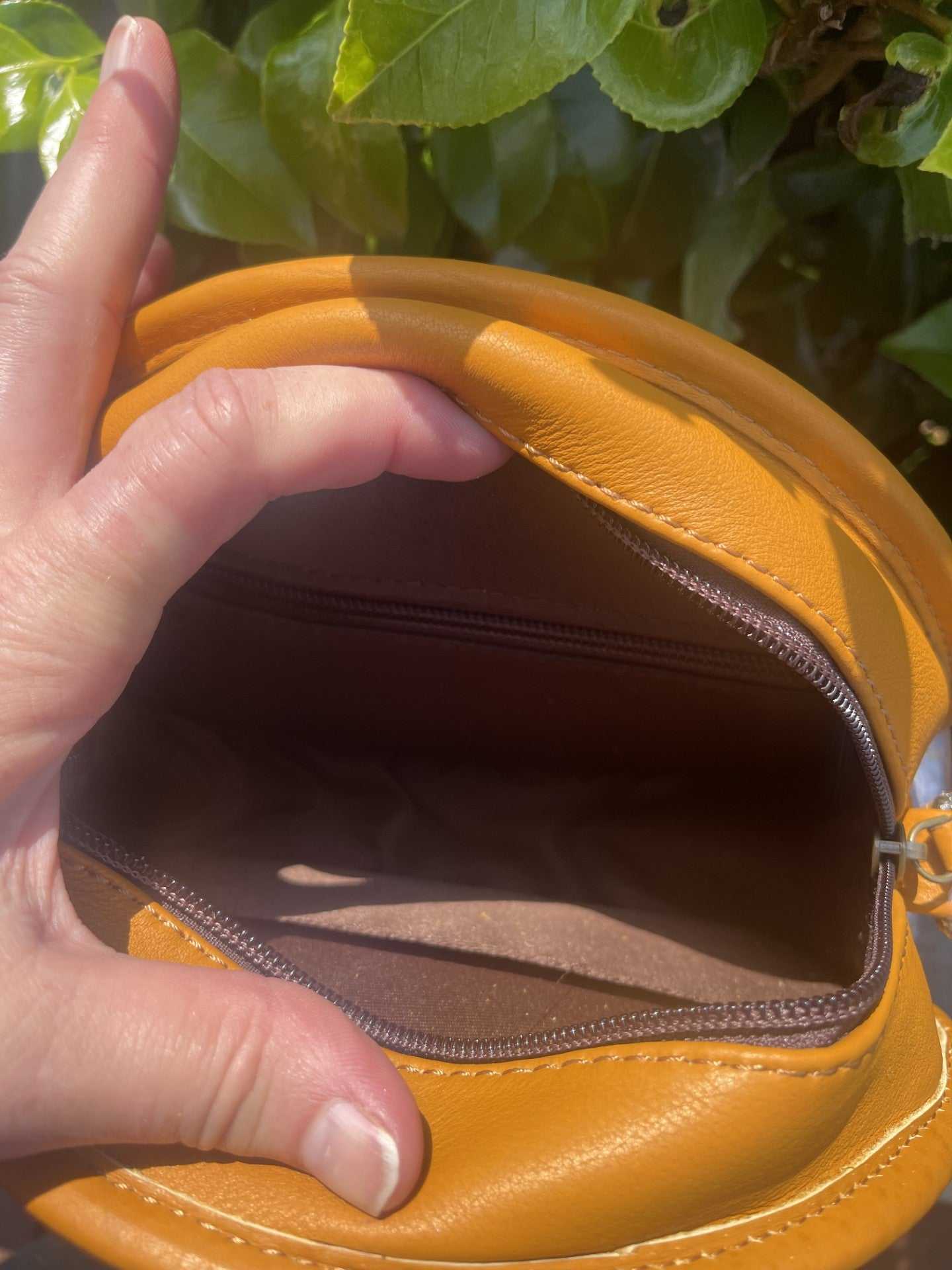 Yellowish-tan sunflower tooled leather crossbody canteen bag with fringe, open showing interior and zipper