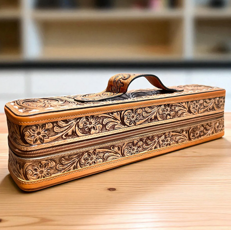 tooled brown leather bracelet-cuff box with floral design and handle on wooden surface