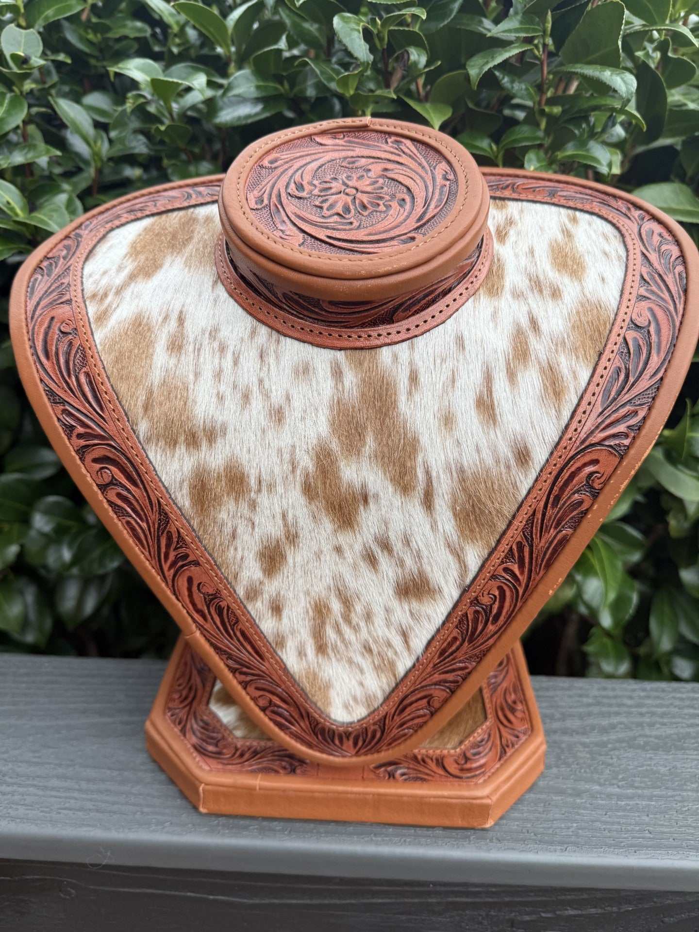 Tan tooled leather and tan white cowhide necklace display with floral detailing