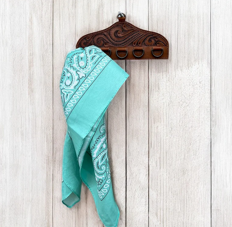 Tooled Scarf Display with intricate designs holding a turquoise paisley scarf on a light wood wall background