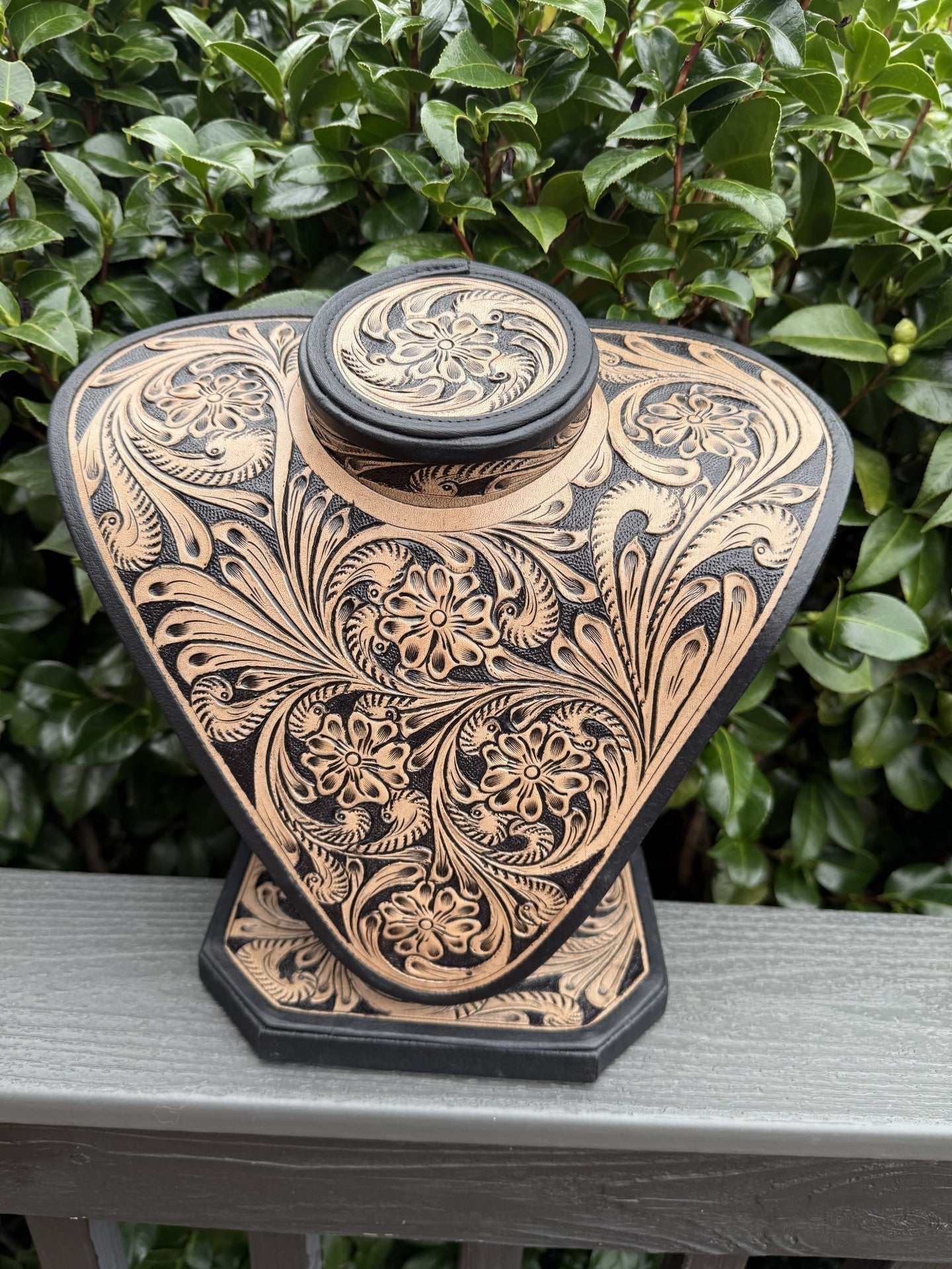 Beige and brown all tooled leather necklace display with intricate floral patterns