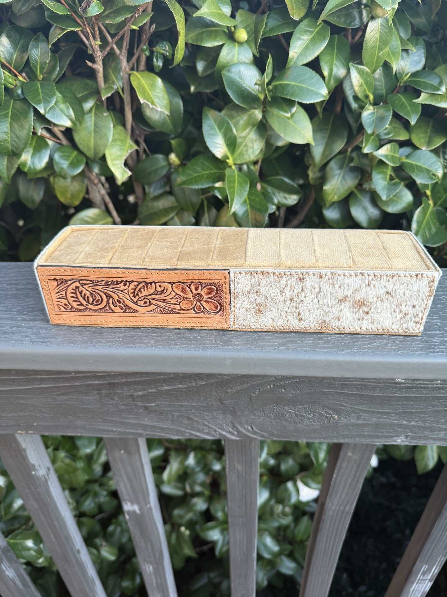 Cowhide and tooled leather ring holder on wooden surface, elegant rustic decor accessory
