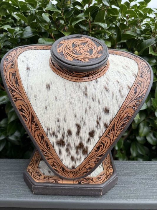 Necklace display with dark brown tooled leather and dark brown and white cowhide background