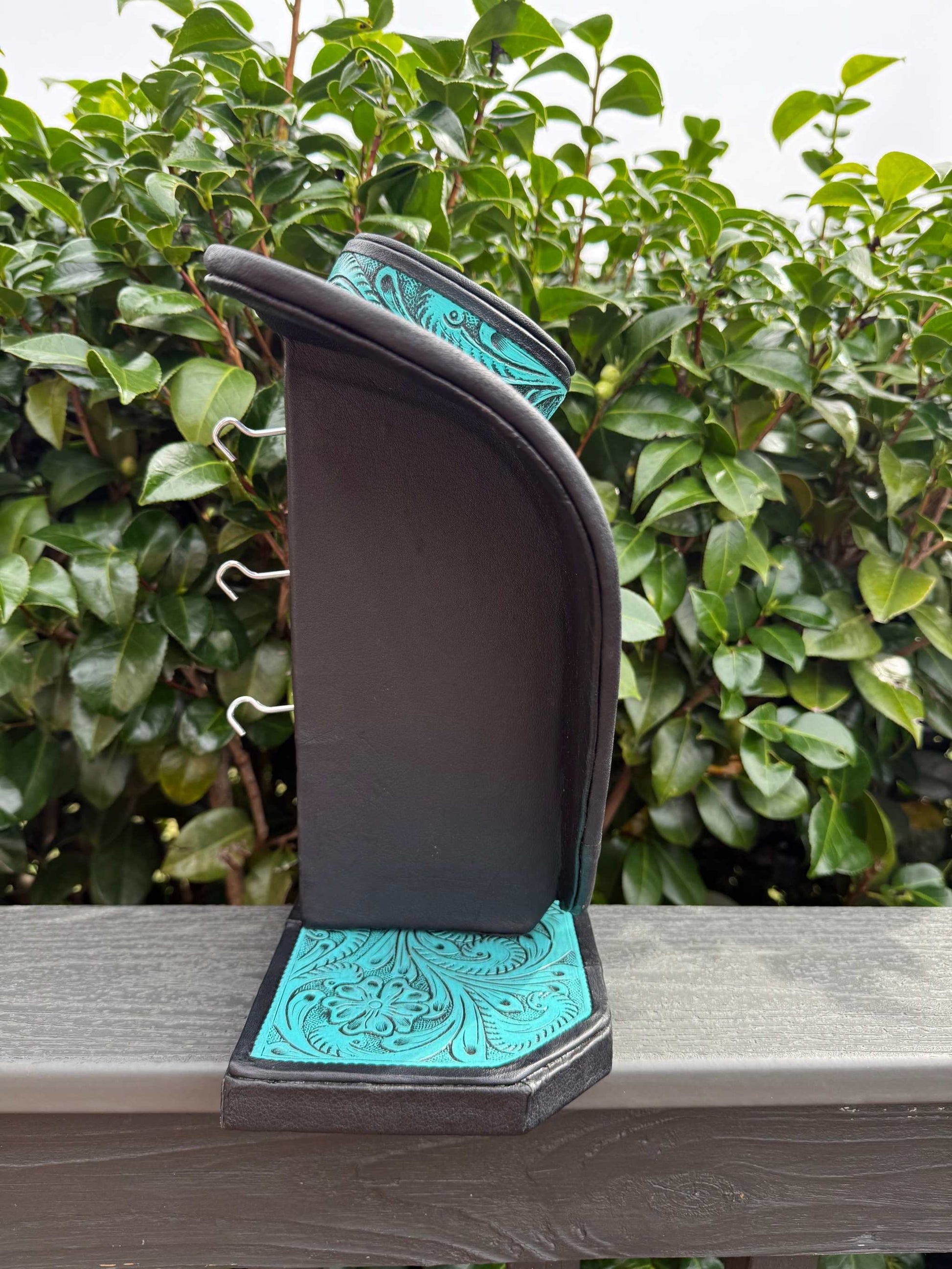 Turquoise and brown all tooled leather necklace display with intricate floral design on leather base and backrest, elegant jewelry organizer.