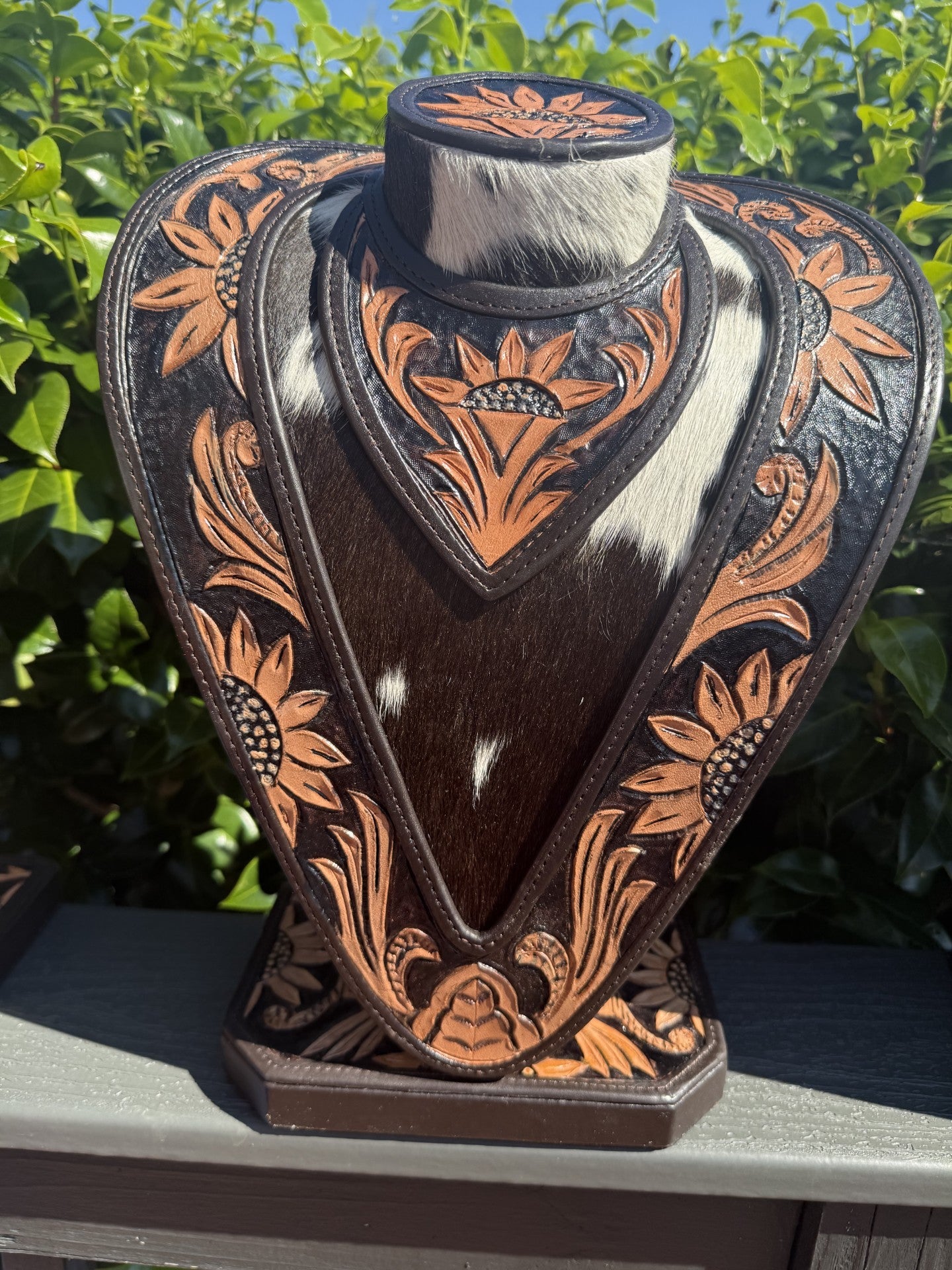 hand tooled leather necklace display with black tan cowhide