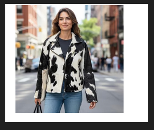 Woman wearing medium black and white cowhide jacket with fringe on city street