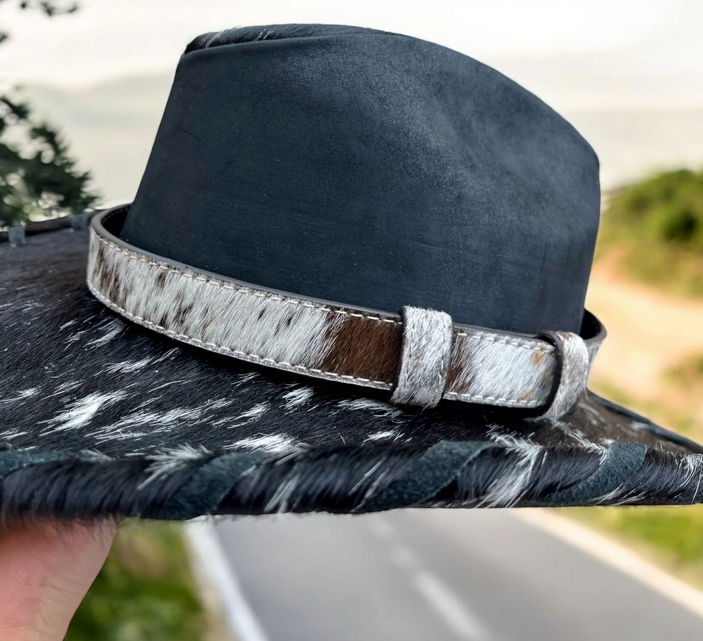 Genuine leather hat band with cowhide pattern on a black hat.