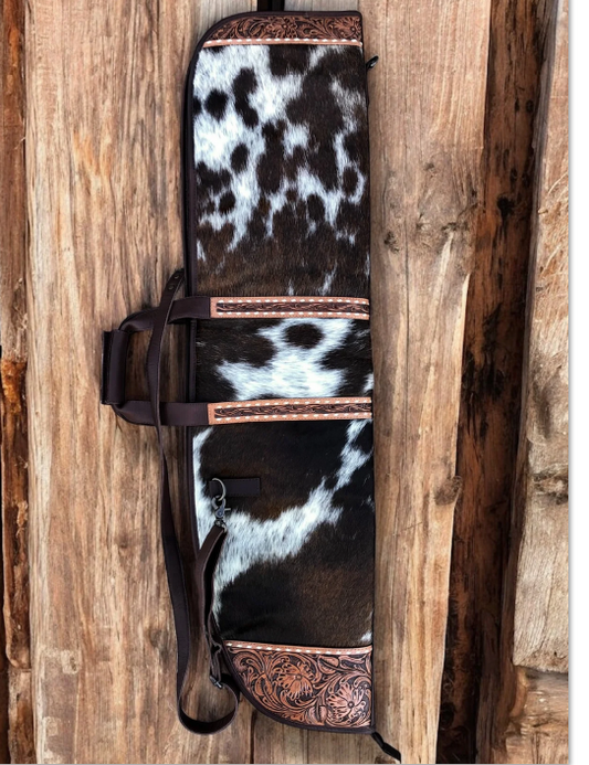 Cowhide tooled leather carrying case with patchwork design on a wooden background.