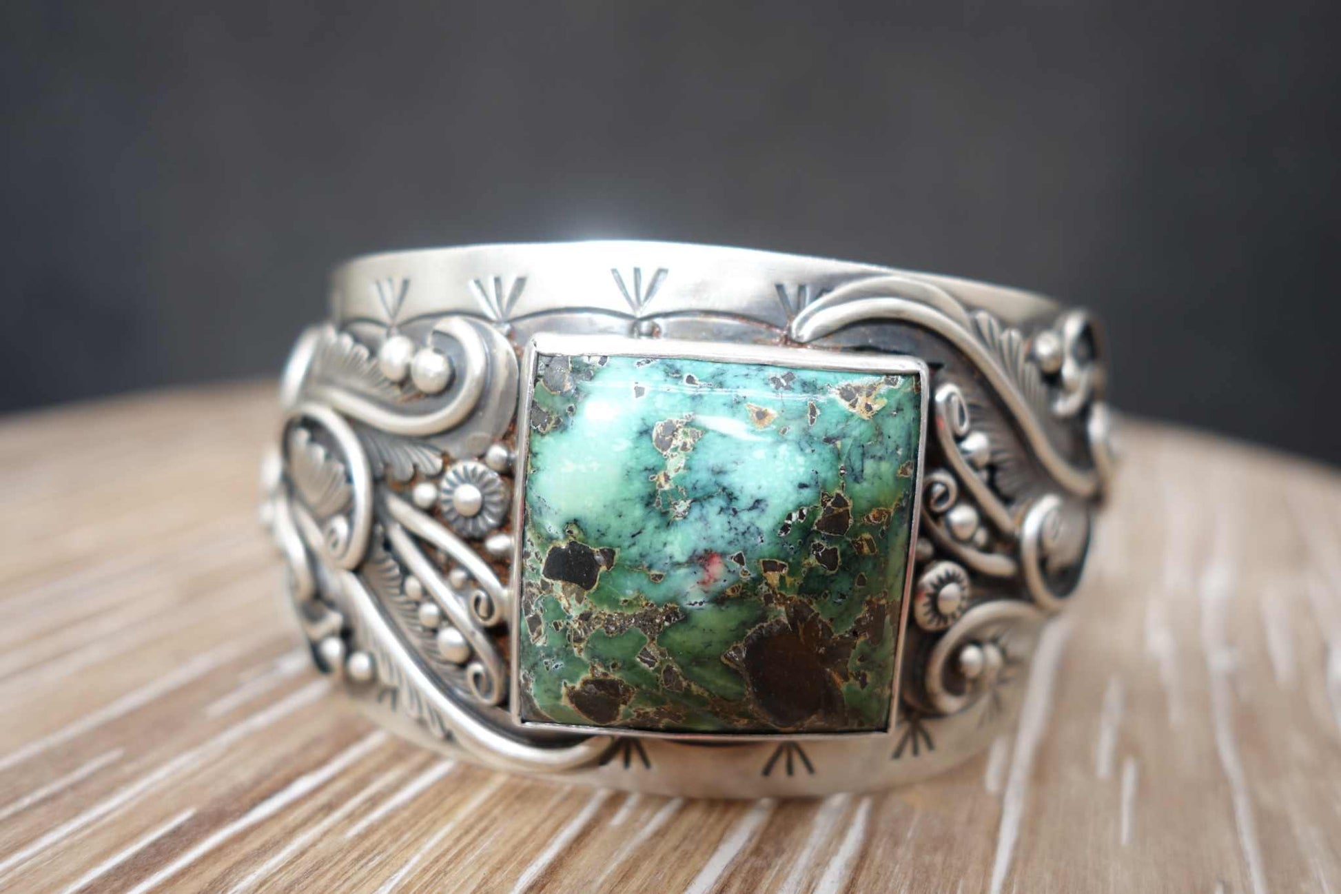 Sterling silver cuff with a square green Blue Moon turquoise stone and intricate designs.