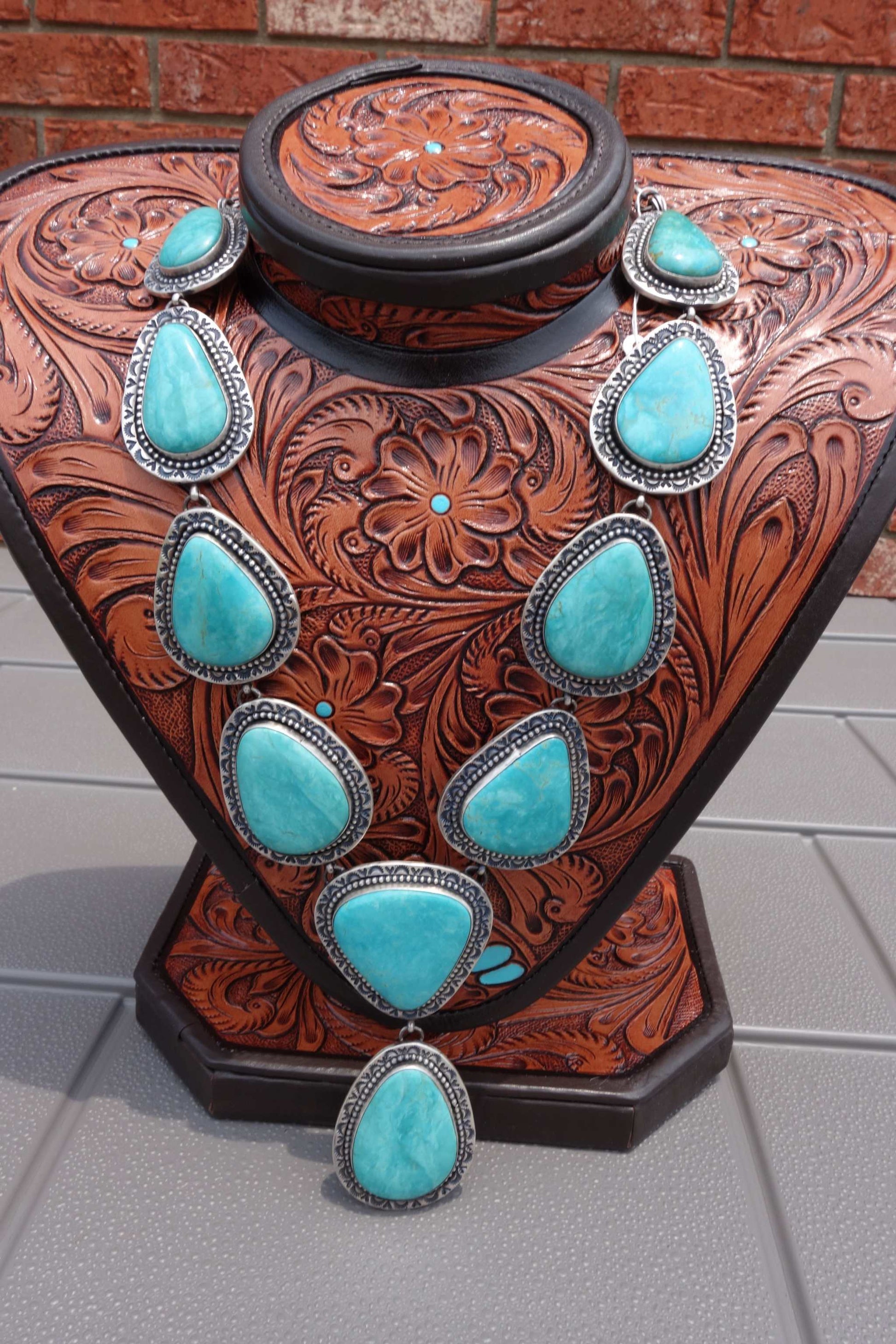 Heavy sterling silver necklace with Armenian turquoise stones on a decorative stand.