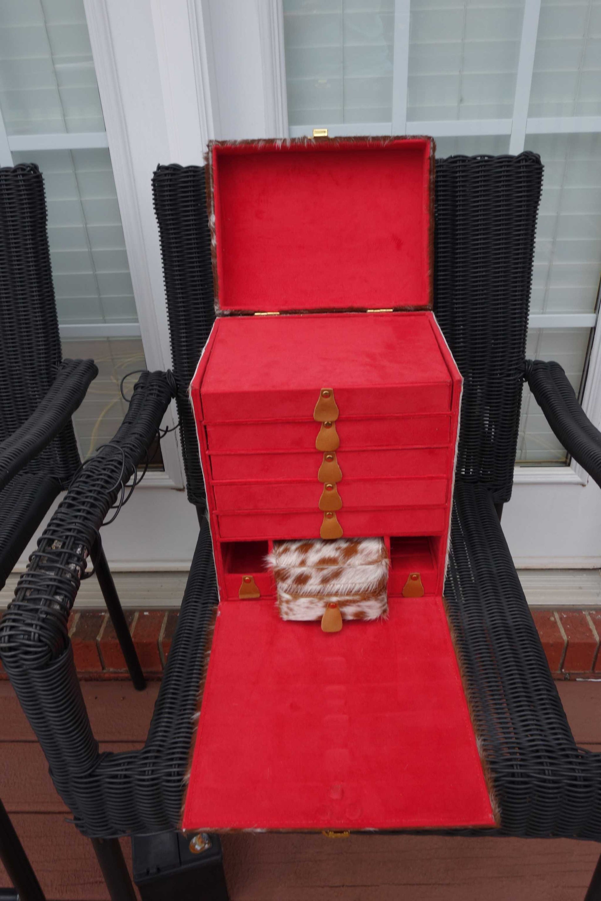 Cowhide Train Jewelry Case with multiple drawers displayed on a chair.
