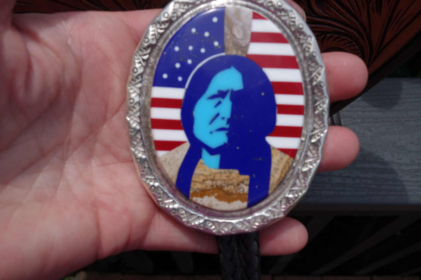 Calvin Desson Navajo handmade silver bolo with Sitting Bull inlay and American flag background featuring turquoise and various stones