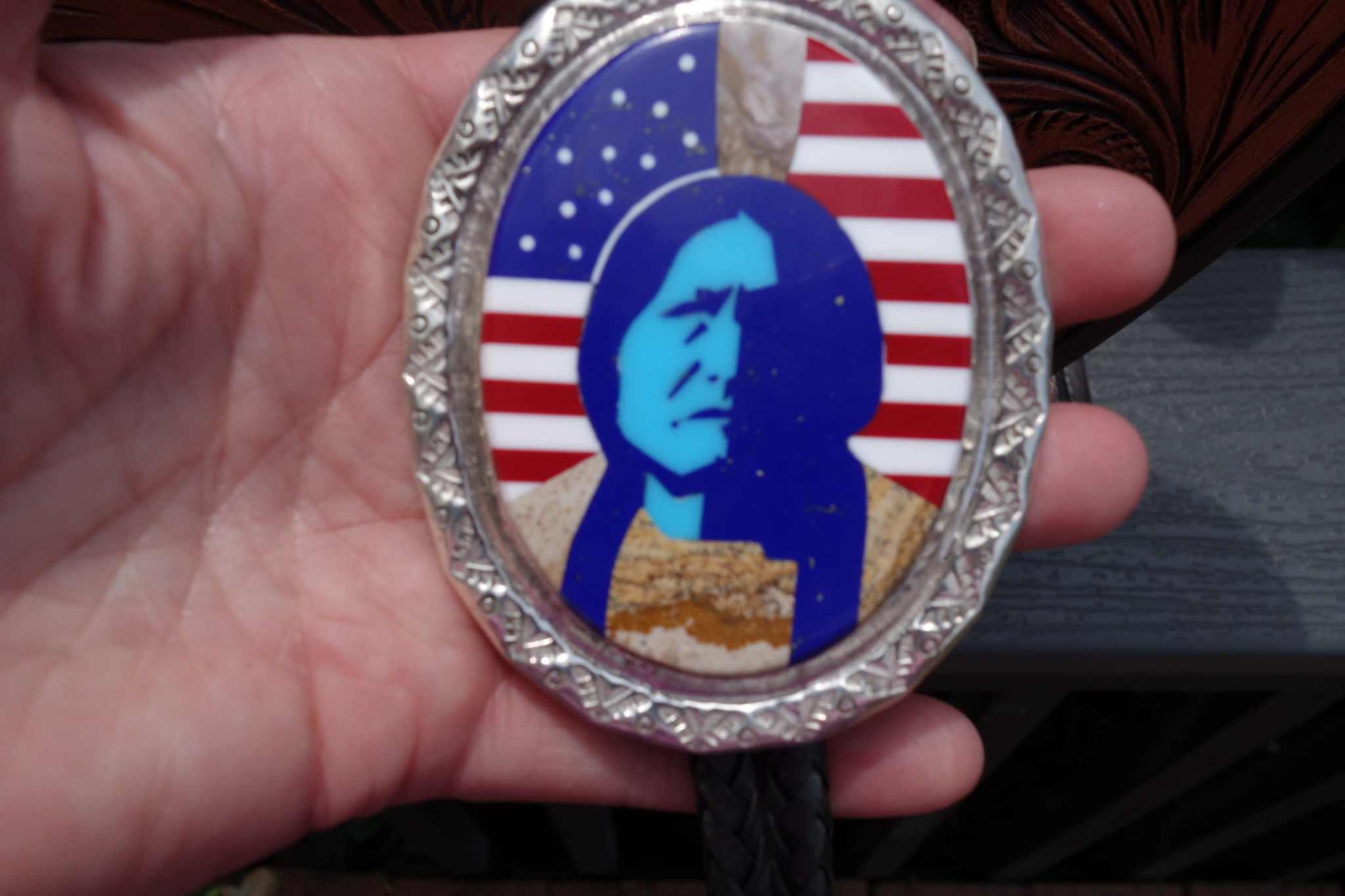 Calvin Desson Navajo handmade silver bolo with Sitting Bull inlay and American flag background featuring turquoise and various stones