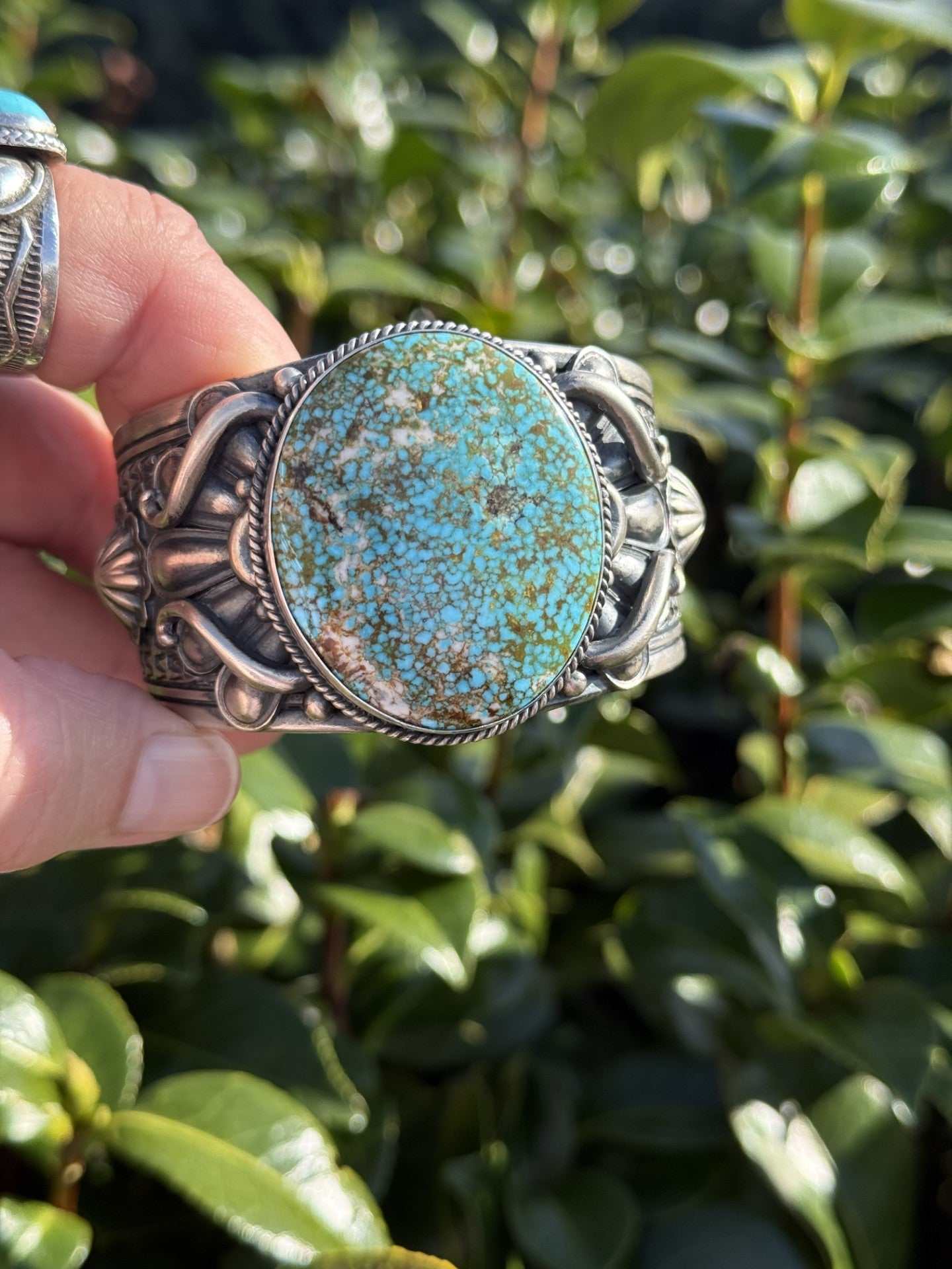 Turquoise Mountain Cuff by Derrick Gordon made of ingot silver with large turquoise stone, detailed silverwork design