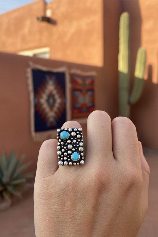 Drop and Turquoise Adjustable Ring featuring silver metal with two turquoise stones and raised silver bead accents in a rectangular design