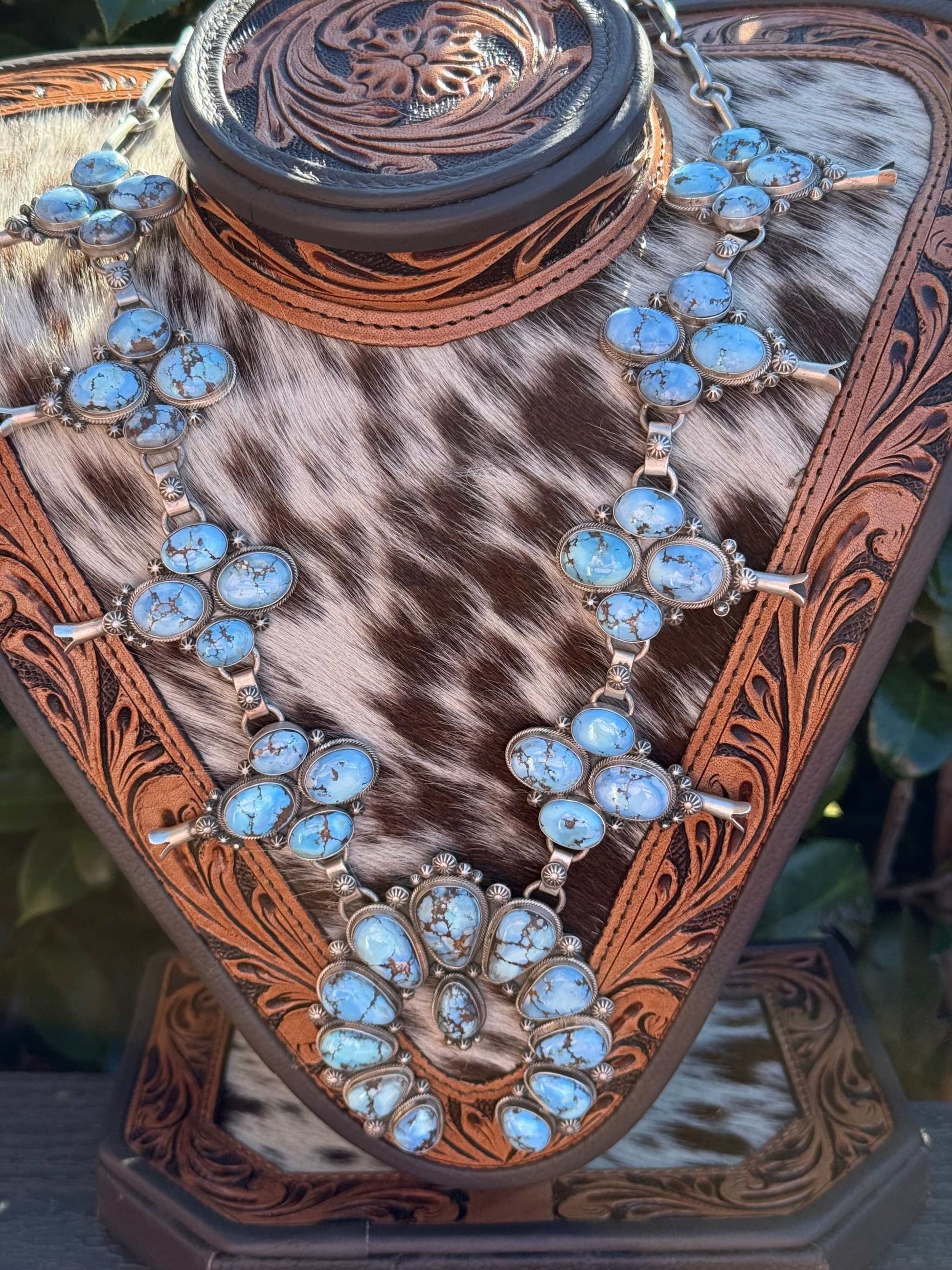 Golden Hills Squash Blossom necklace with turquoise stones and silver detailing on leather display