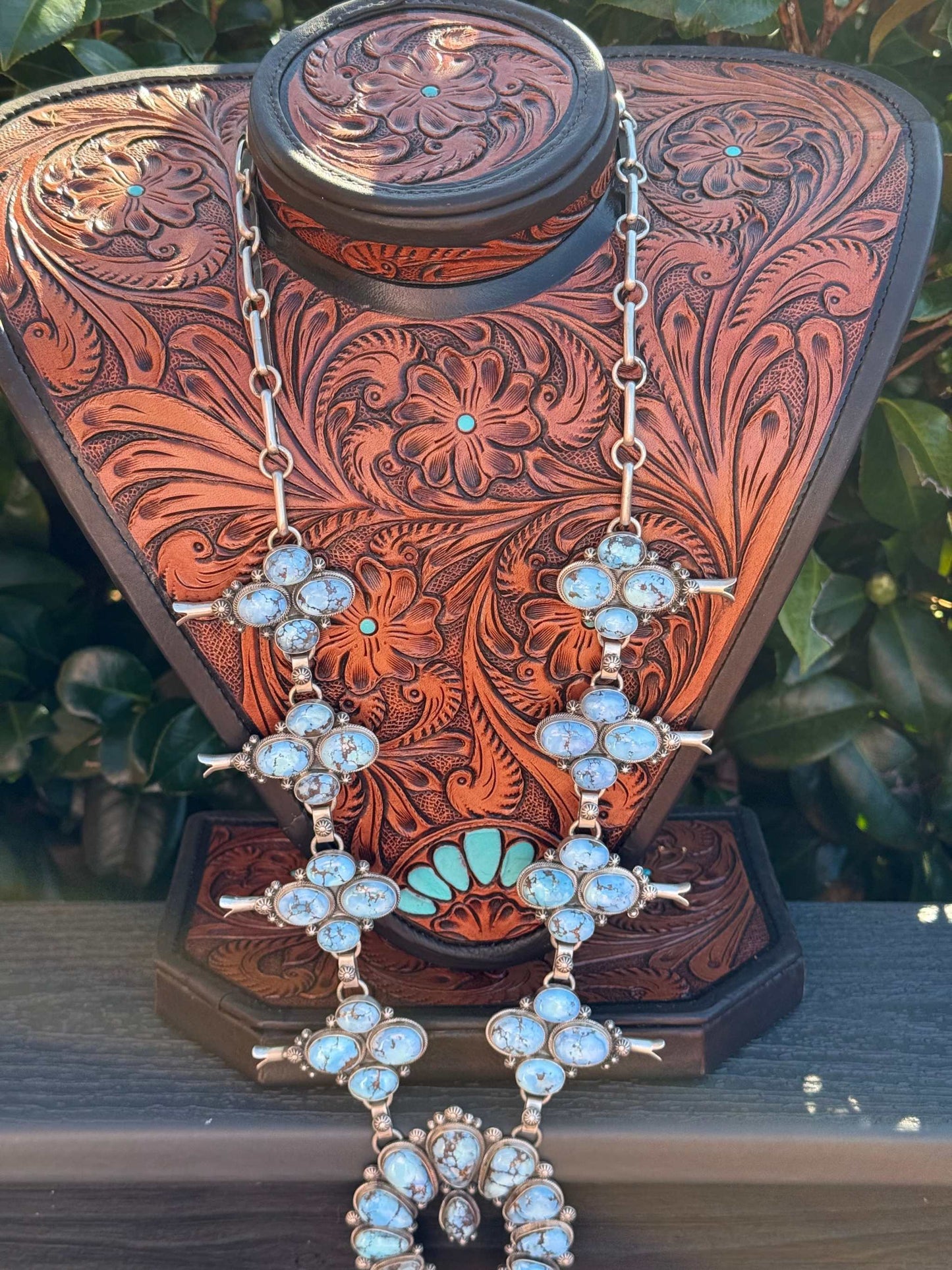 Golden Hills Squash Blossom necklace statement piece with turquoise stones on carved leather display