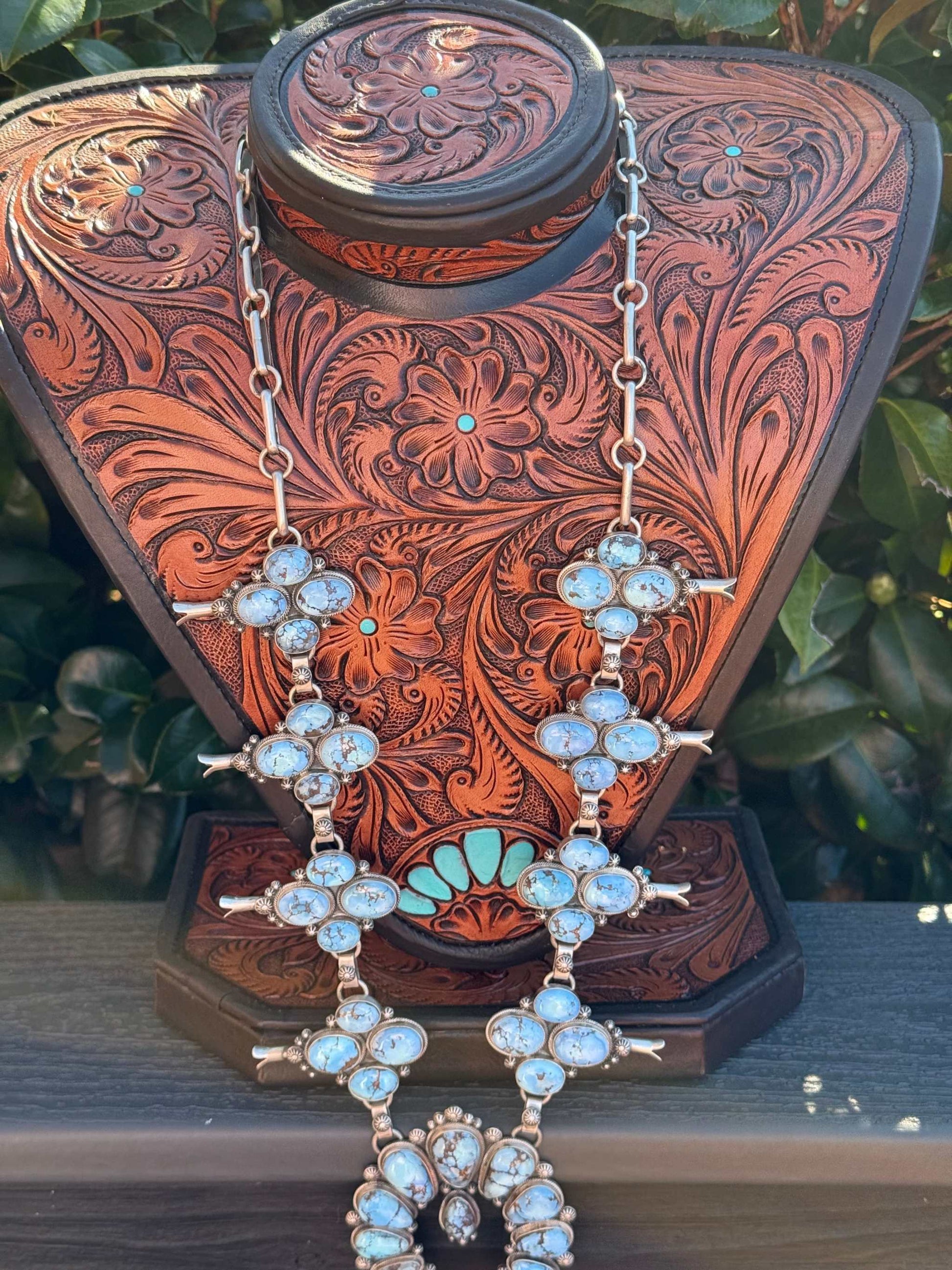 Golden Hills Squash Blossom necklace statement piece with turquoise stones on carved leather display