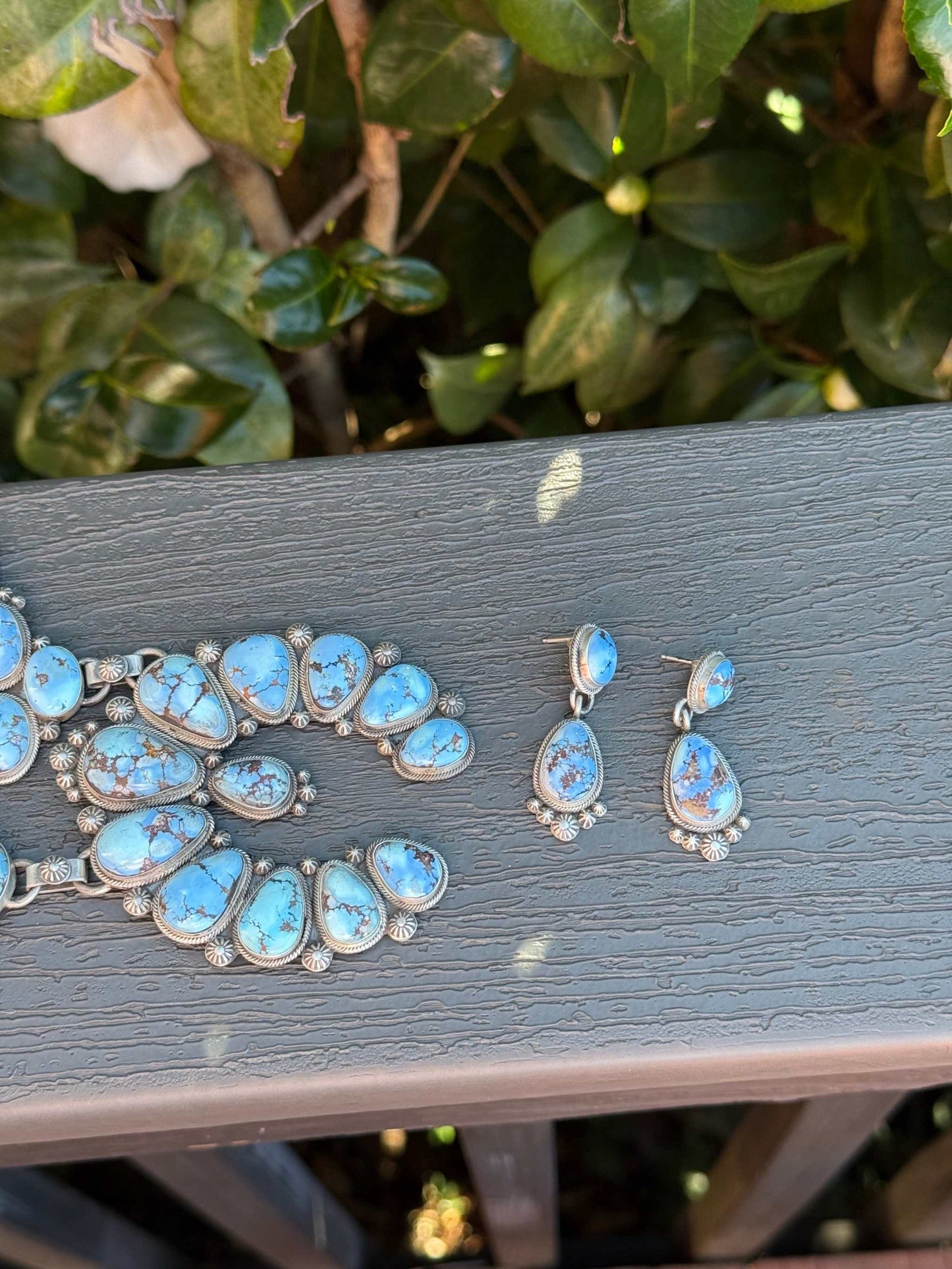 Golden Hills Squash Blossom turquoise necklace and earrings set by Freddie Maloney displayed on wooden surface