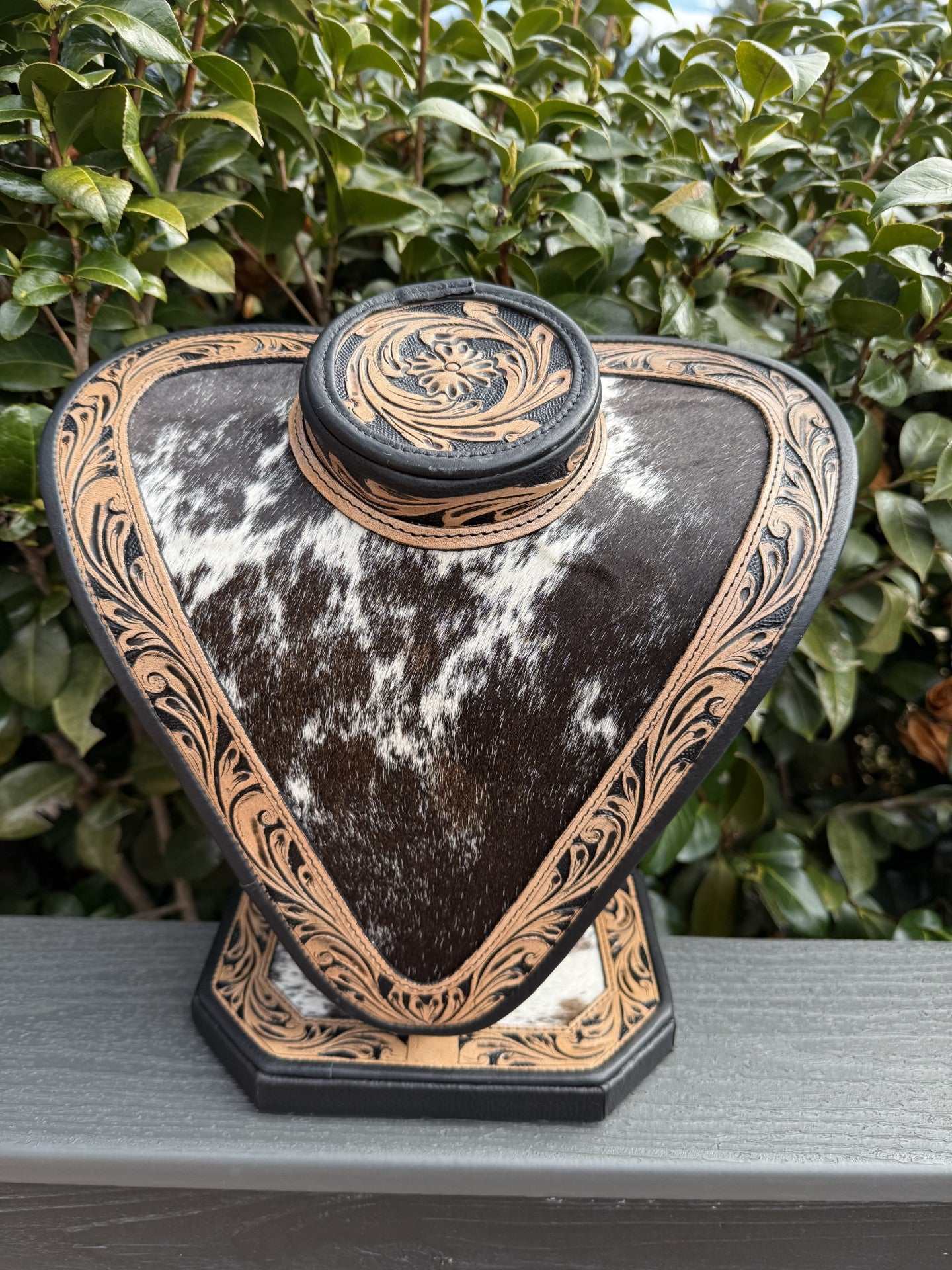 Necklace display featuring dark and light brown tooled leather with black and white cowhide accents showcasing jewelry.