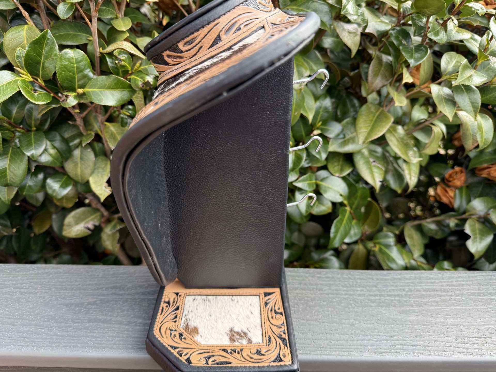 Necklace display in dark and light brown tooled leather with black and white cowhide accents
