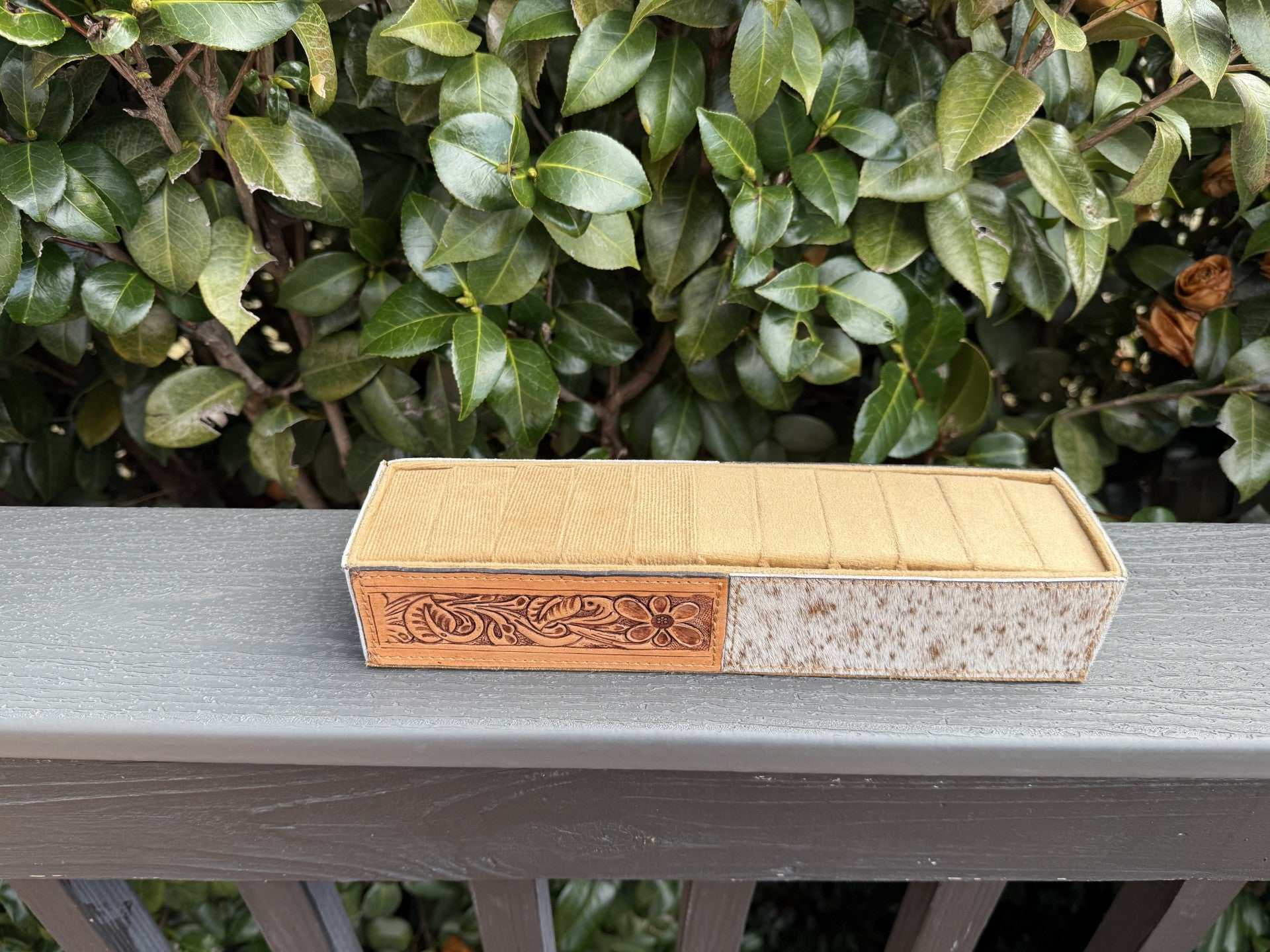 Cowhide and tooled leather ring holder on a wooden surface showcasing elegant craftsmanship