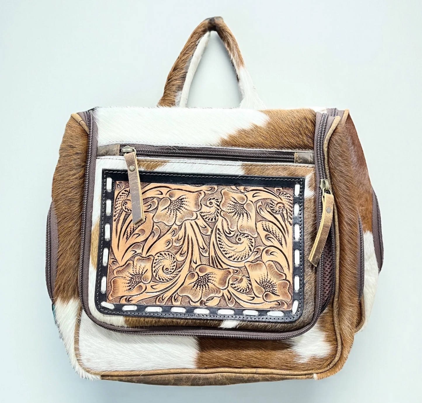 Tooled and cowhide hanging toiletry bag with hand-tooled leather and multiple compartments for travel and gym organization