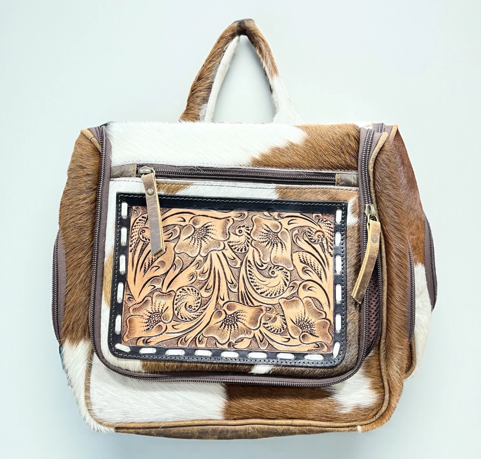 Tooled and cowhide hanging toiletry bag with hand-tooled leather and multiple compartments for travel and gym organization