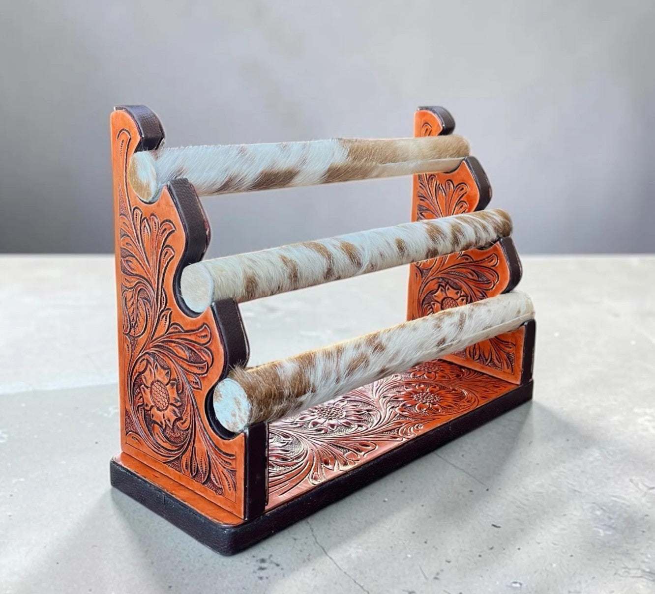Rustic cowhide and tooled leather bracelet display for western jewelry organization