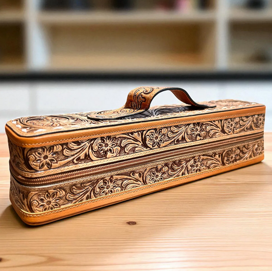 tooled brown leather bracelet-cuff box with floral design and handle on wooden surface