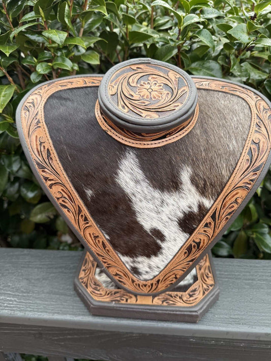 Necklace display with dark and light brown tooled leather and black and white cowhide pattern