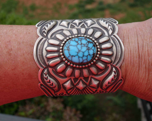 Sterling silver Egyptian turquoise Cuff featuring intricate stamped patterns and a large blue turquoise stone centerpiece on a wrist