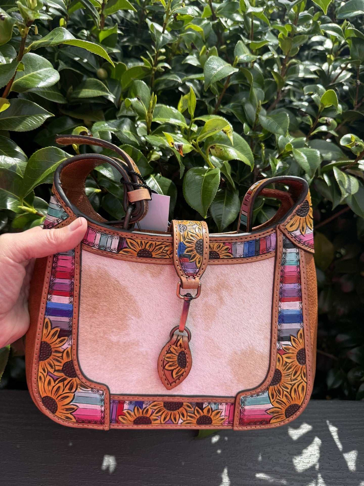 Shoulder bag in pinkish tan leather with colorful floral tooling, striped panels and a pale cowhide center; Floral tooled leather detailing