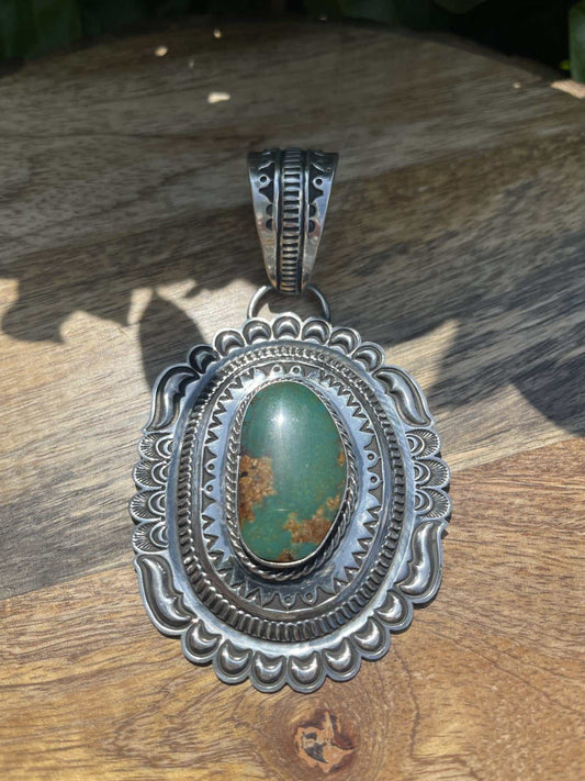 Native American Green Pilot Mountain Turquoise pendant with intricate silver detailing and polished green turquoise stone