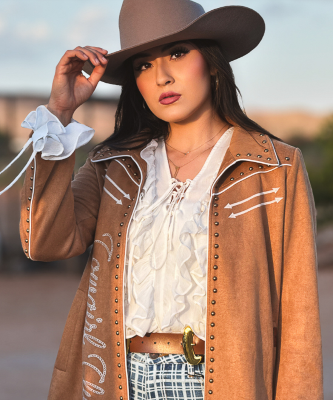 Ivory Long Sleeve blouse with white ruffled front, lace-up neckline and ruffled cuffs beneath a brown Western jacket