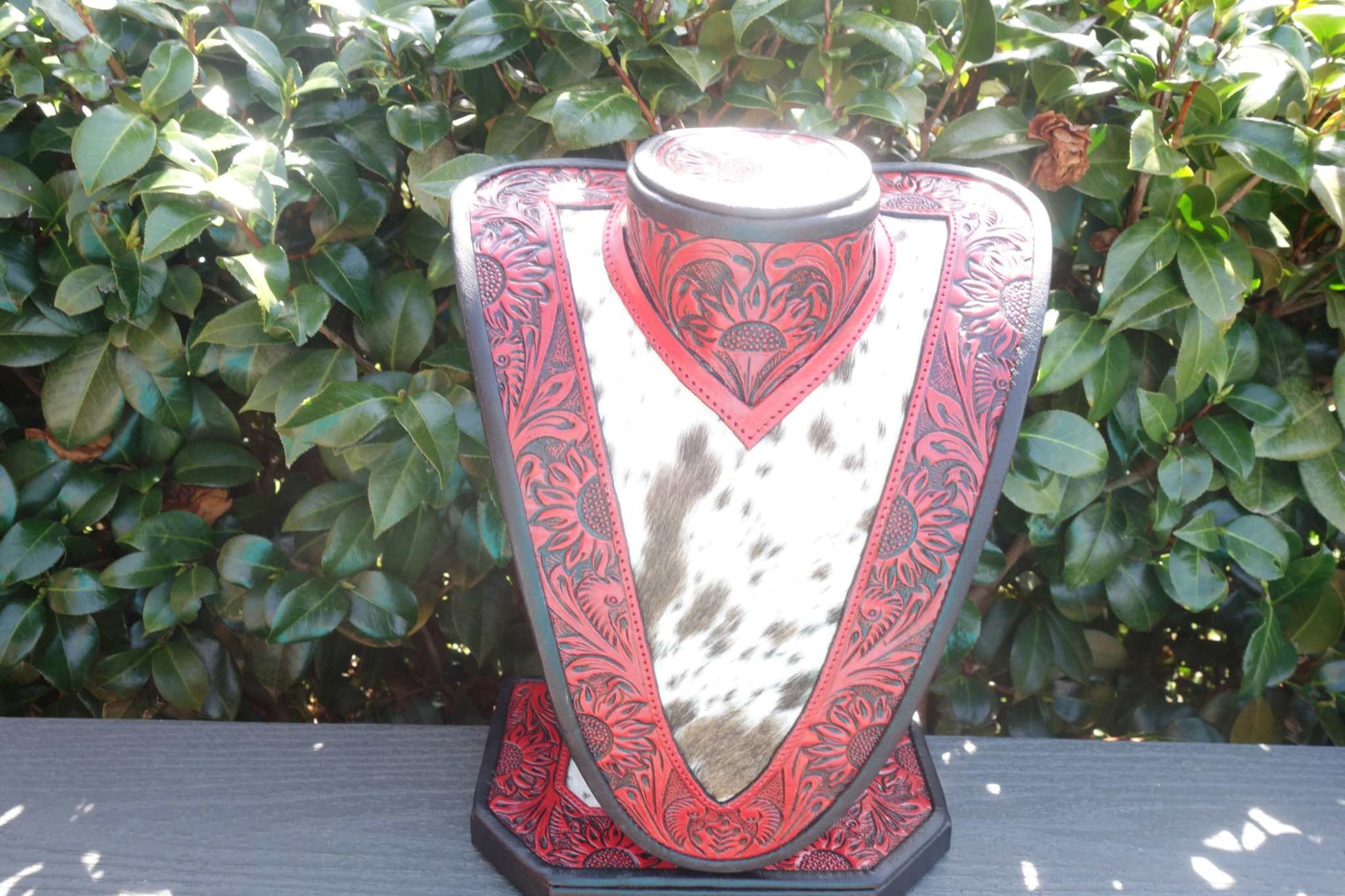 Med Necklace Display with red tooled leather and brown white cowhide showcasing necklaces
