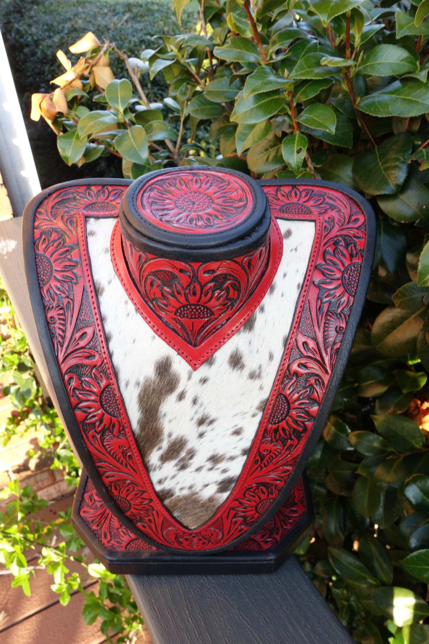 Med Necklace Display featuring red tooled leather and brown and white cowhide