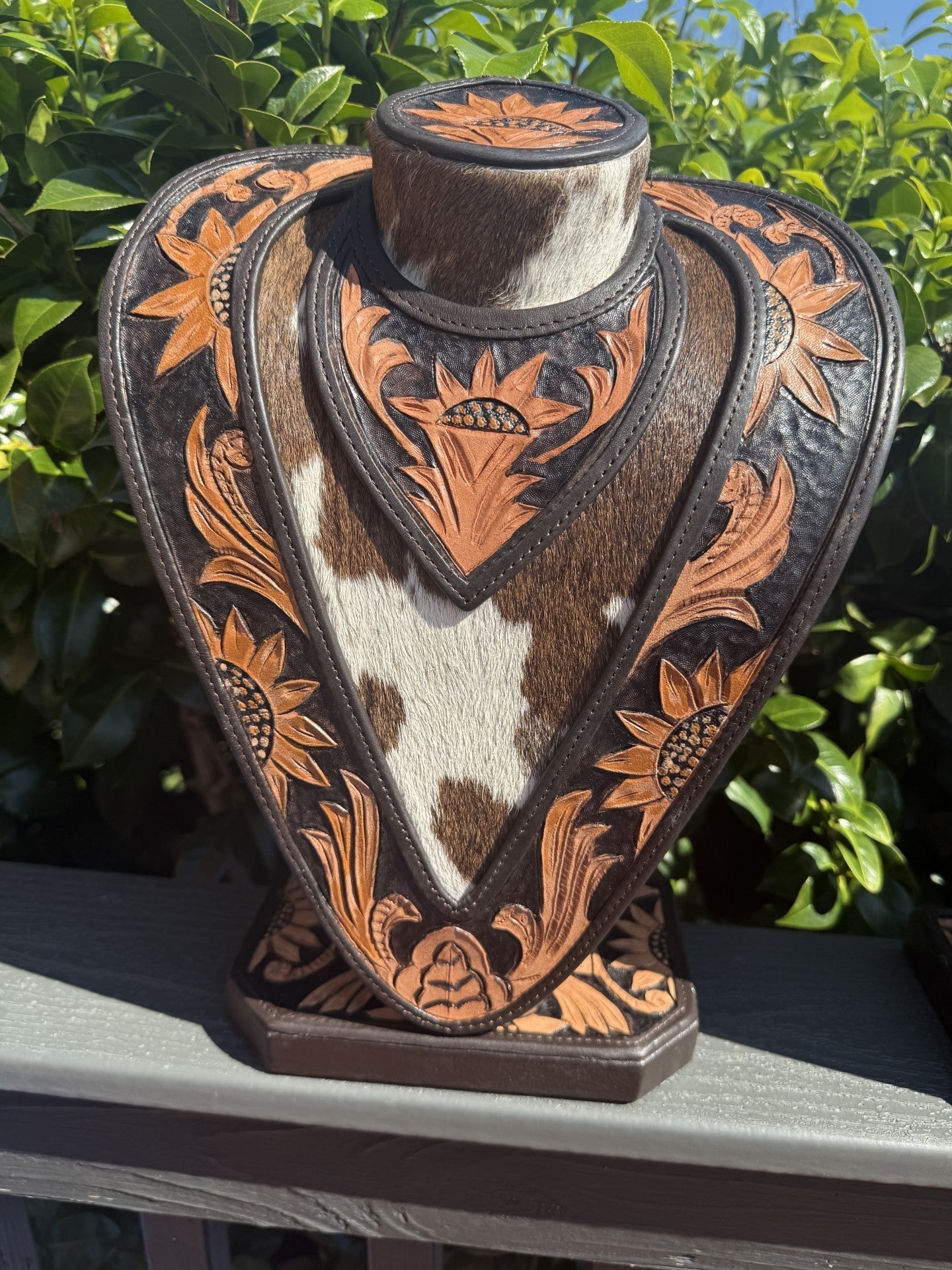 Hand tooled black and tan leather necklace display with cowhide