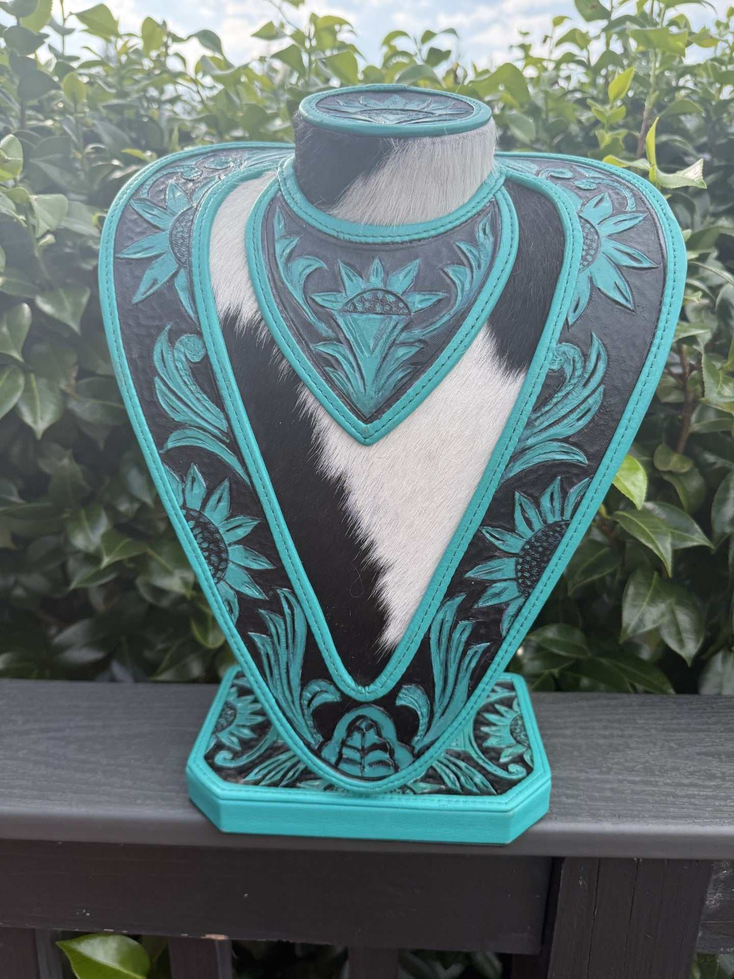 Green turquoise and black hand tooled leather necklace display with cowhide accents