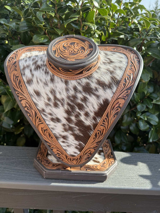 Necklace display with dark brown tooled leather and dark brown and white cowhide pattern