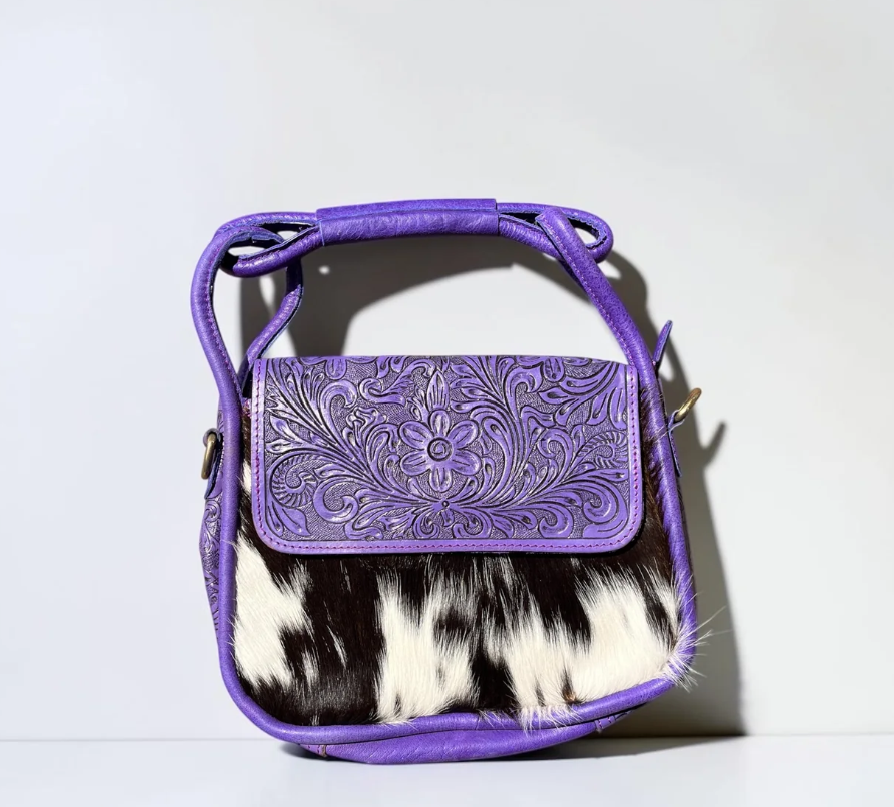 Shoulder bag in Purple tooled leather with embossed floral pattern, purple trim, and contrasting black-and-white cowhide panel