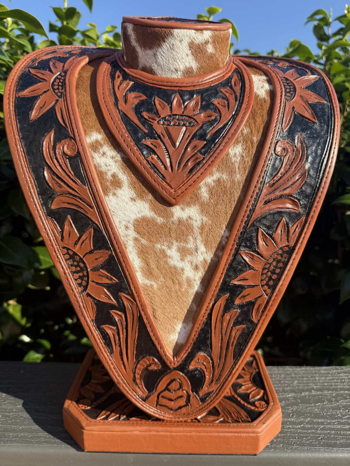 Necklace Display in saddle tan and black leather with hand tooled floral patterns and genuine cowhide accents, showcasing craftsmanship.