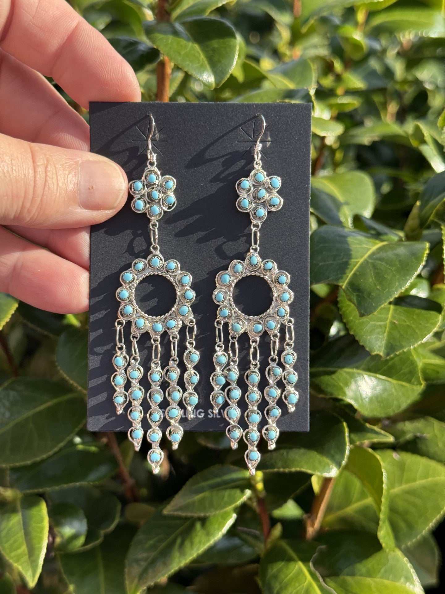 Snake Eye Earrings by Navajo artist Wayne Johnson with turquoise dangles and unique design outdoors