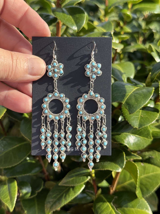 Snake Eye Earrings by Navajo artist Wayne Johnson with turquoise dangles and unique design outdoors