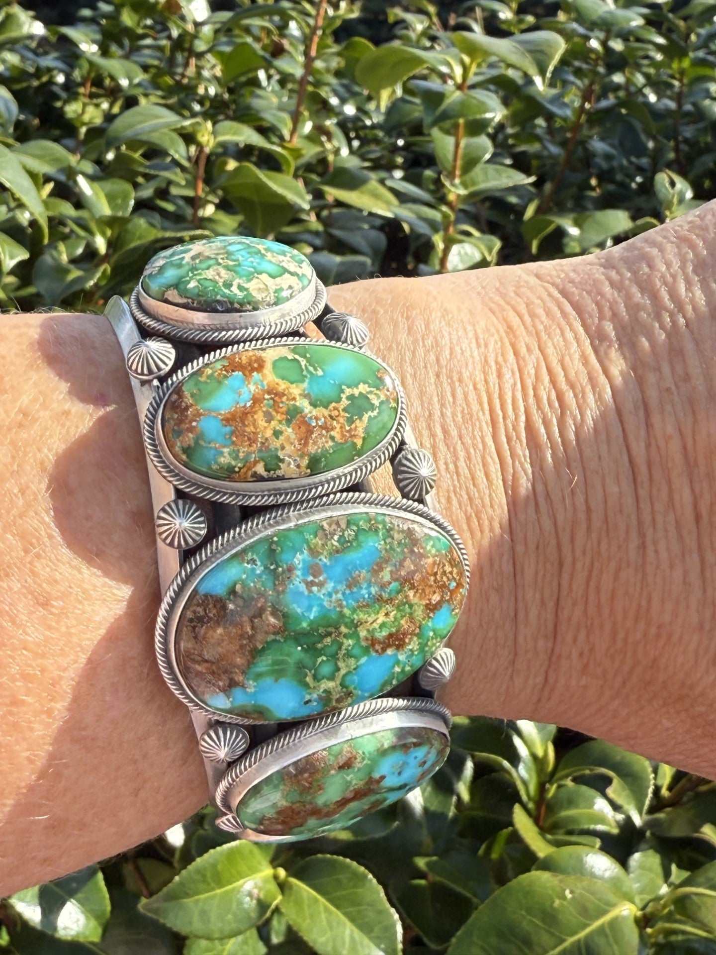 Gorgeous Sonoran Gold Turquoise Cuff handcrafted by Navajo artist with vibrant green, blue, and golden stones on wrist