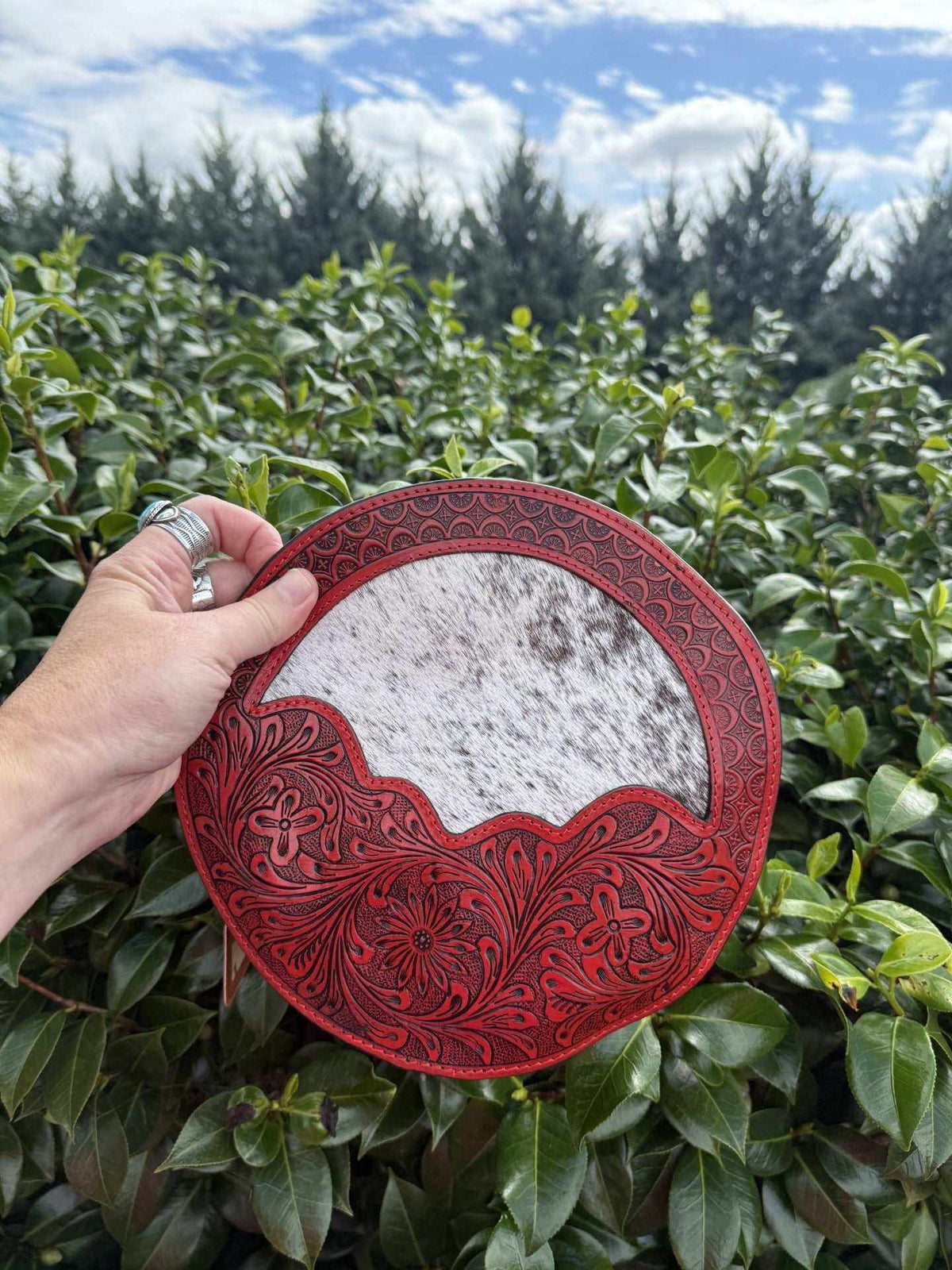 Canteen bag in Tooled leather & cowhide, featuring red floral tooling and a white-and-gray cowhide center