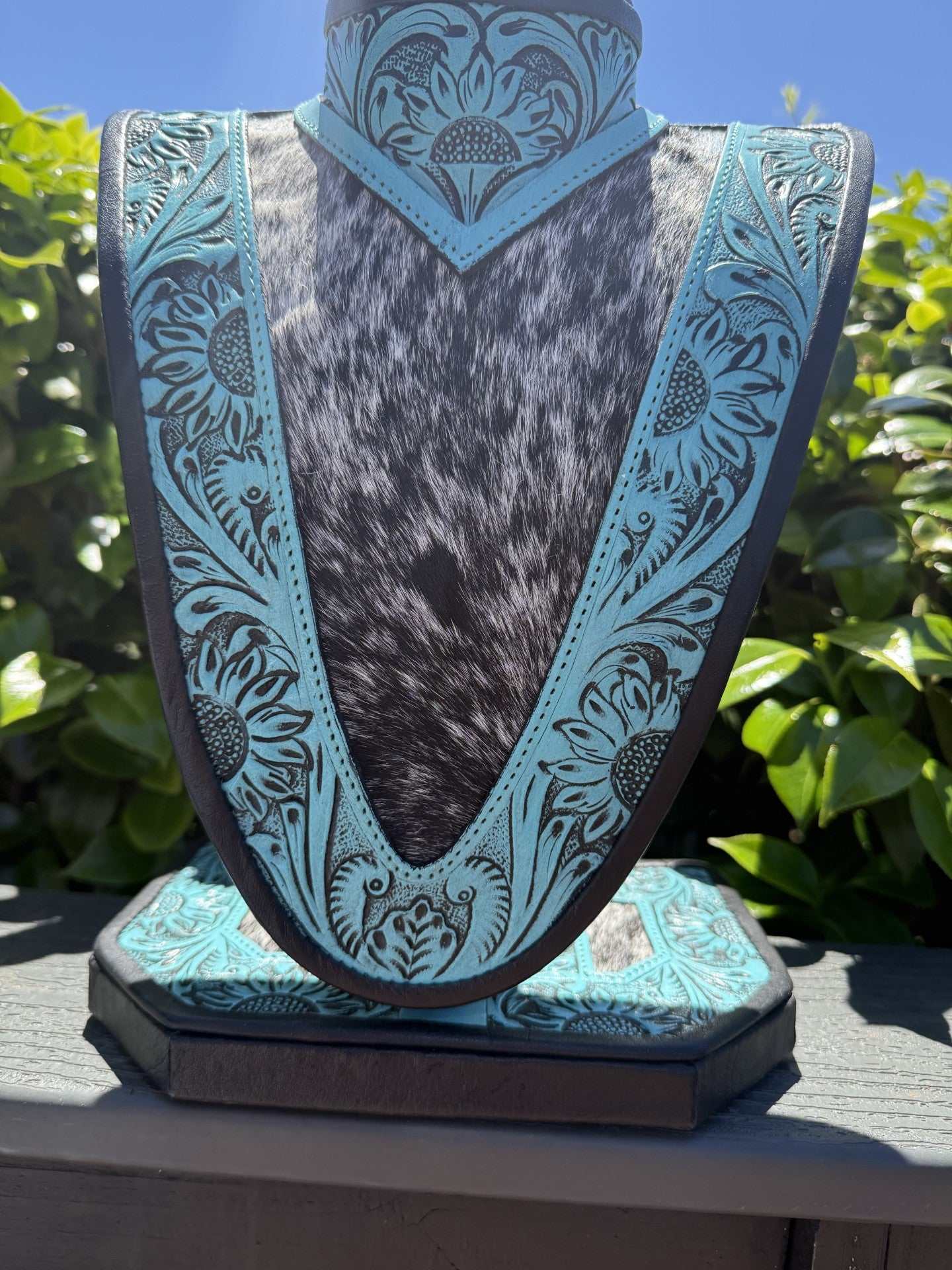 Medium Turquoise tooled leather necklace display with black and white cowhide background