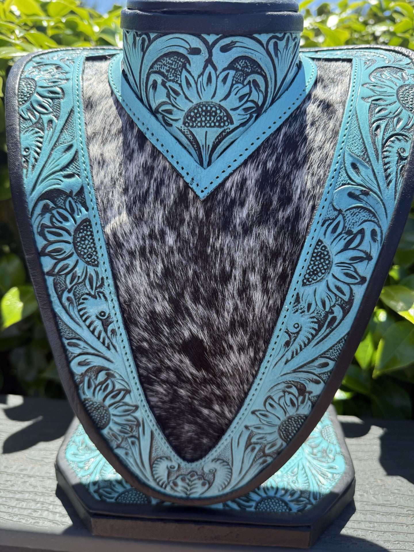 Medium turquoise tooled leather necklace display with black and white cowhide background
